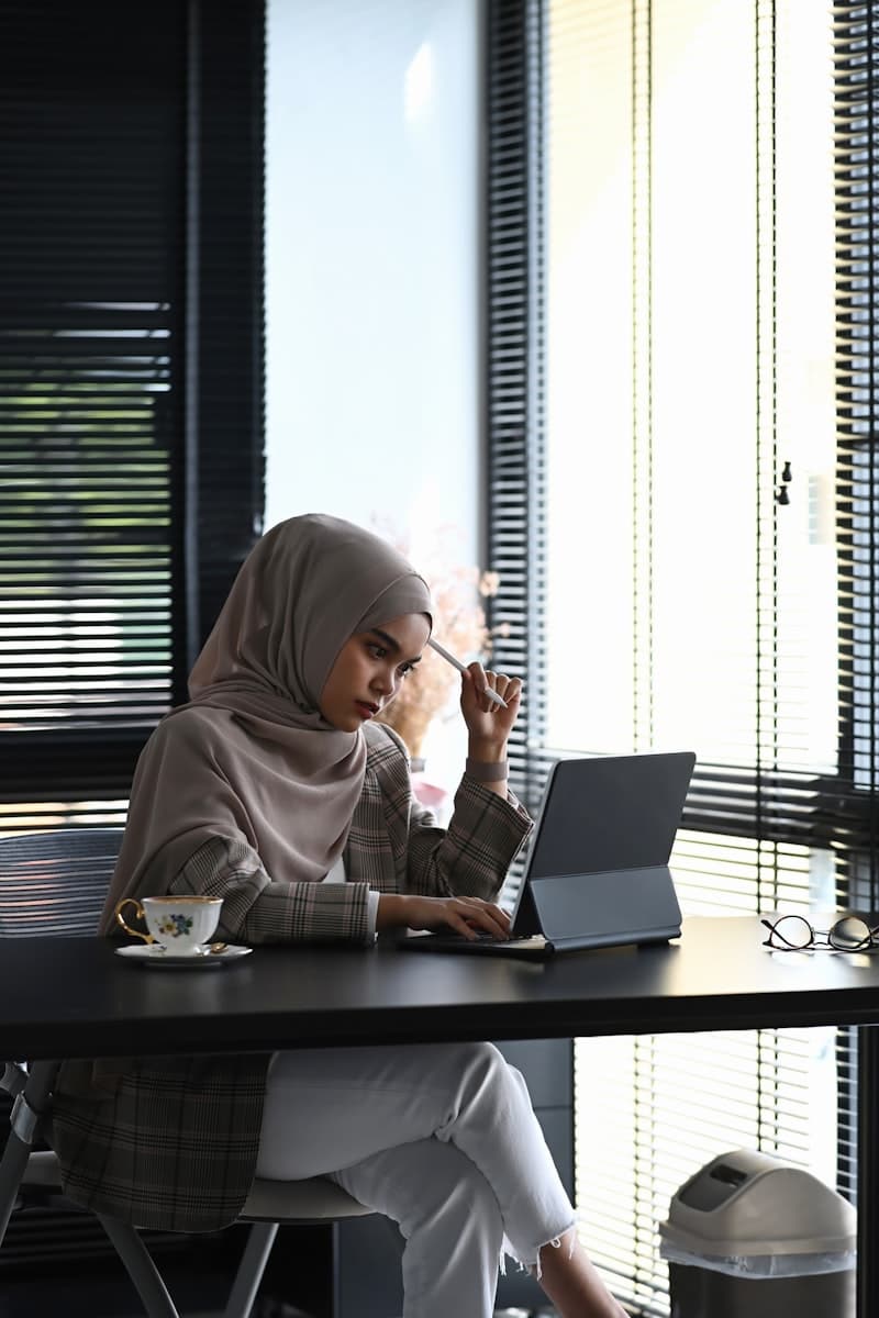 Hijab-wearing businesswoman taking notes at office desk
