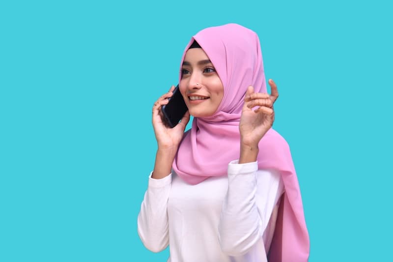 Wanita berhijab merah muda menunjukkan bagaimana warna terfoto dengan latar belakang kontras