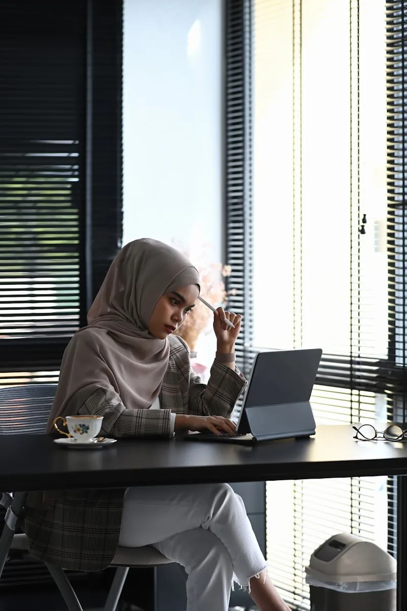 Hijab-wearing businesswoman taking notes at office desk