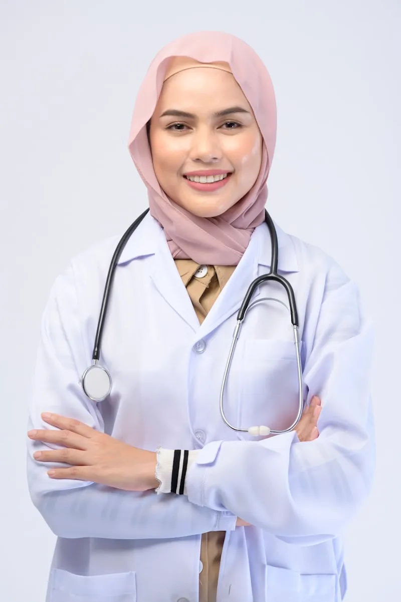 Muslim doctor wearing hijab and white coat with stethoscope - professional medical headshot