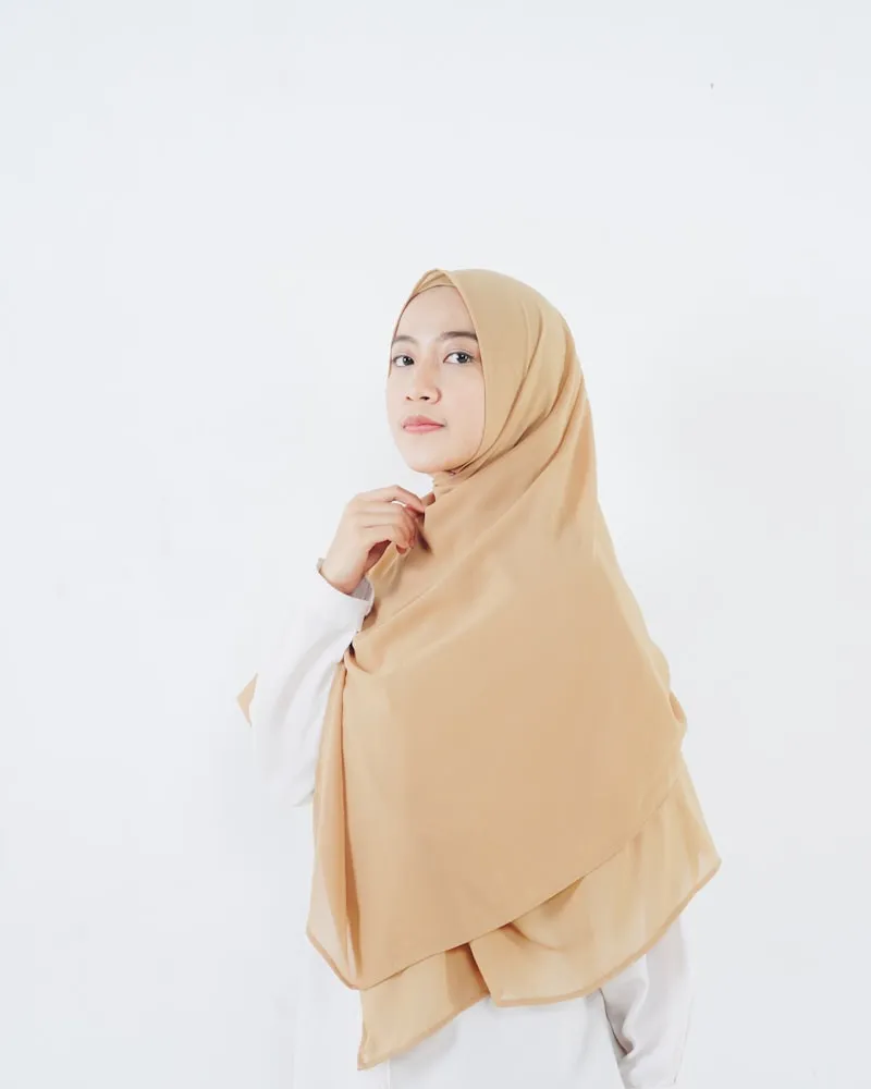 Professional headshot with camel hijab against white background